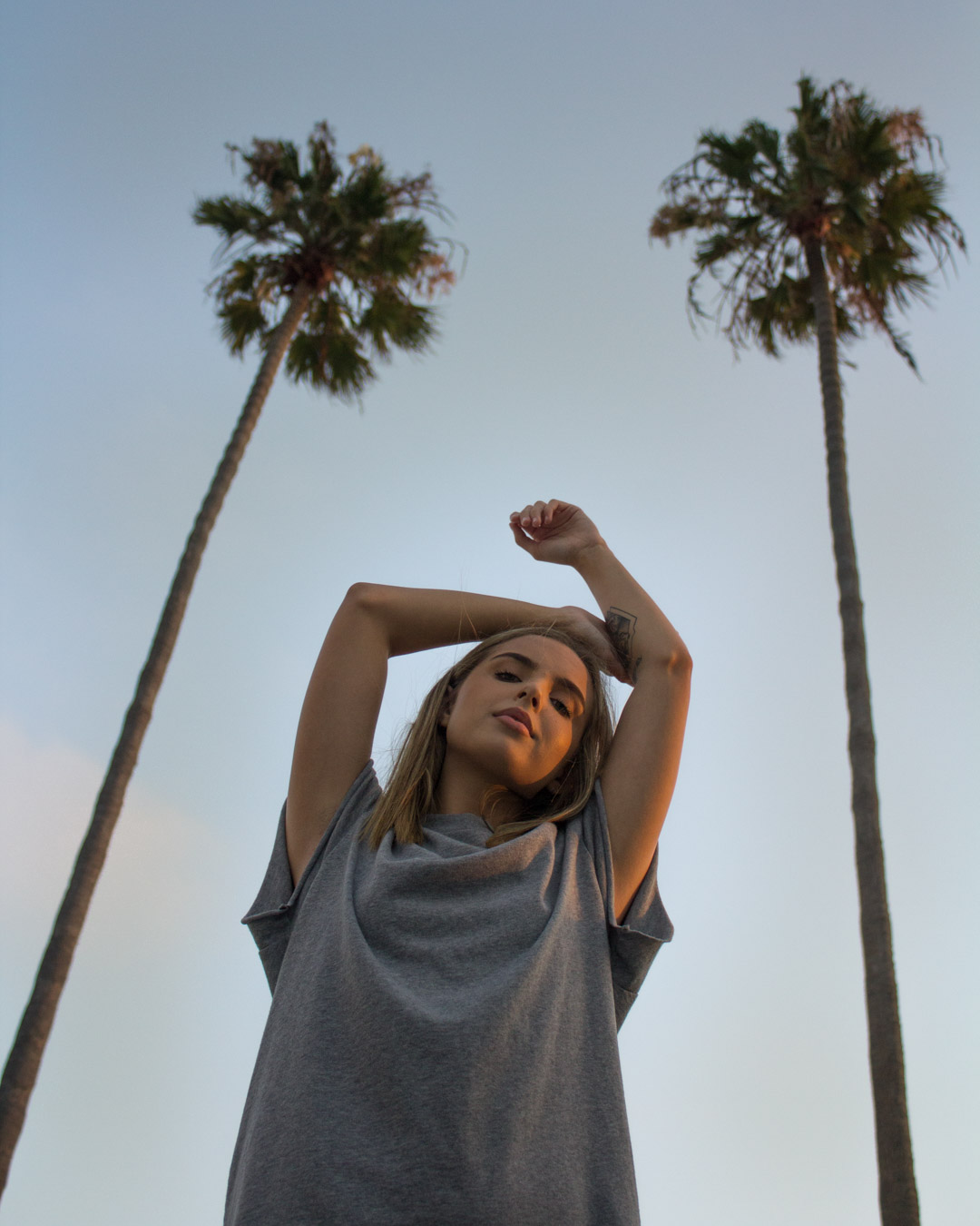 professional photo by nate torres of woman standing between two palm trees